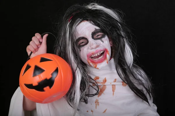 Conceito de horror de Halloween. bonito pouco assustador menina no monstro zumbi traje com abóbora no preto fundo . — Fotografia de Stock