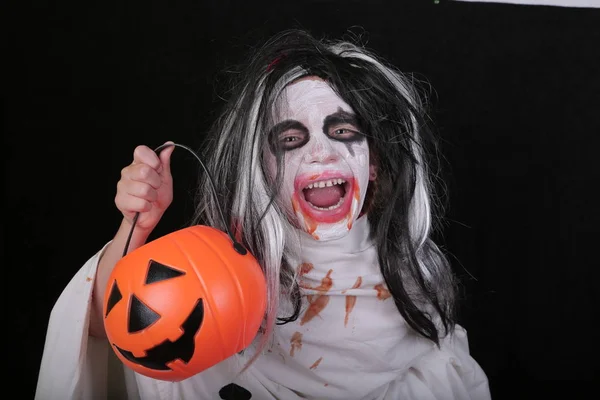 Halloween horror fogalmát. Aranyos kis ijesztő lány szörny zombi jelmez sütőtök a fekete háttér. — Stock Fotó
