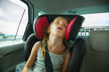 Arabada çocuk güvenlik koltuğunda uyuyan güzel sarışın kız. Çocuk taşıma güvenliği.