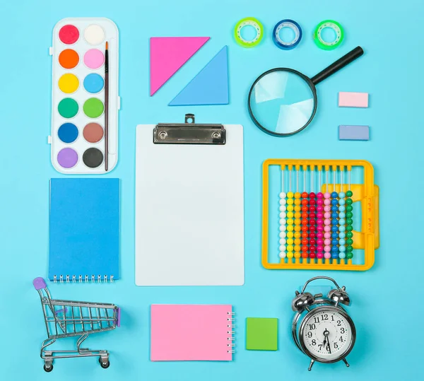 Torniamo al concetto di shopping scolastico. Materiale scolastico su sfondo blu. Layout piatto, vista dall'alto, spazio di copia. — Foto Stock