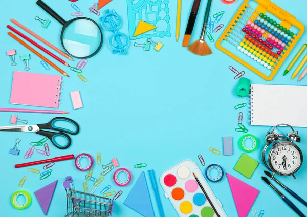 Torniamo al concetto di shopping scolastico. Materiale scolastico su sfondo blu. Layout piatto, vista dall'alto, spazio di copia. — Foto Stock