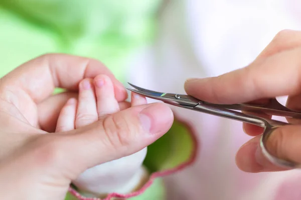 Moeder is tiny nagels netjes en voorzichtig aan de kant van de pasgeboren baby die met behulp van nagelschaartje snijden. Concept van zorg moeder voor baby. — Stockfoto