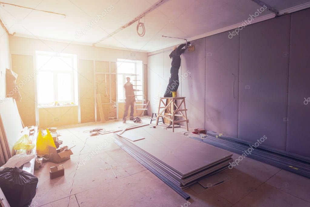 Workers are installing plasterboard drywall for gypsum walls in apartment is under construction, remodeling, renovation, extension, restoration and reconstruction
