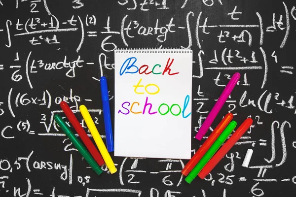 Powrót do szkoły tło z tytułu powrót do szkoły, napisane na stronie biały Notebook na tablicy z formuł matematycznych napisał kredą na tablicy i kolorowe pisaki — Zdjęcie stockowe