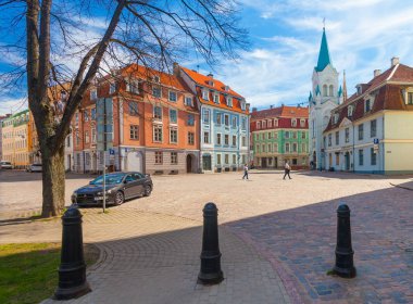 Riga, Letonya - 06 Mayıs 2017: Görünüm renkli rahat eski evleri, kilise, sokak Hediyelik eşya mağazaları ve Riga şehir merkezi bulunan turistler.