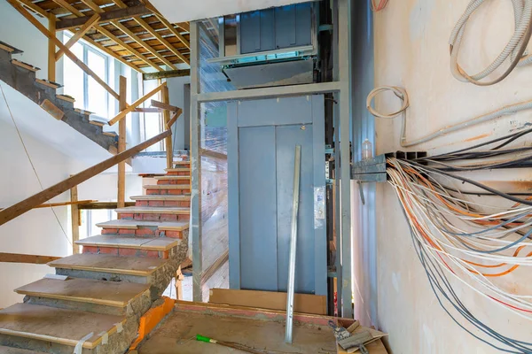 Wall  with wires, stairs with temporary wooden railing and elevator in an apartment is during on the construction, remodeling, rebuilding and renovation. — Stock Photo, Image