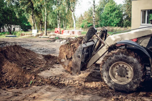 Nowoczesne koparka prac ziemnych na terenie budowy. Zobacz na duże koła brudne koparka i wiadro koparka, która jest pełna gruntu, — Zdjęcie stockowe