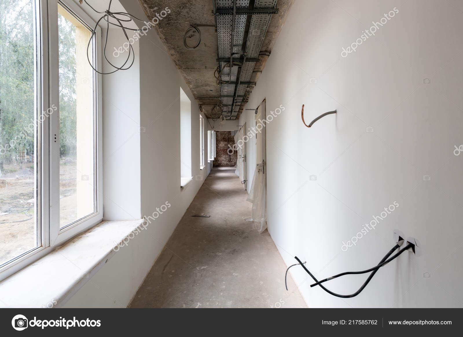 Lang og smal korridor vinduer, døre, kabelbakker og vægge med ikke elektriske kabler i en lejlighed under på opførelse, eftersyn, ombygning, ombygning, boligforbedringer © Zazamaza #217585762