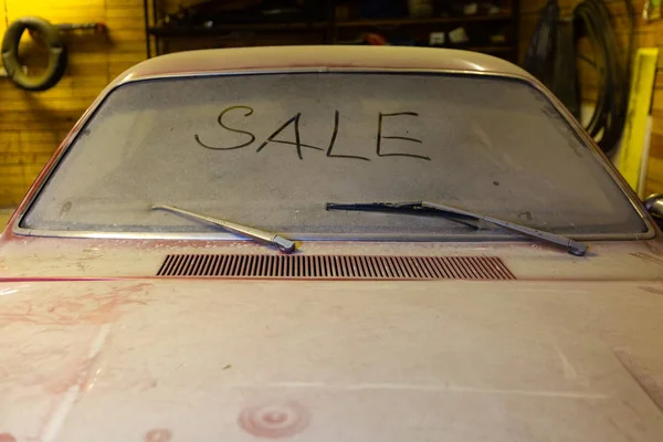 धूलदार हुड गंदी हवा स्क्रीन के साथ गैराज में पुरानी कार का दृश्य उंगली और टूटे हुए विंडशील्ड वाइपर द्वारा शीर्षक बिक्री के साथ। बिक्री पूर्व मालिक कारों की अवधारणा . — स्टॉक फ़ोटो, इमेज