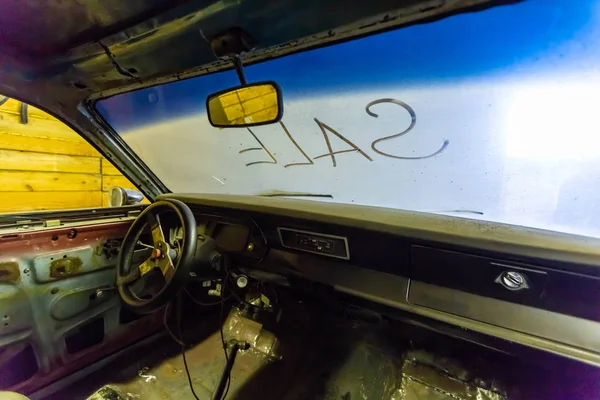 Vista interior del interior del coche viejo roto con el tablero polvoriento del vehículo, espejo trasero, volante de conducción y pantalla de viento sucio con título VENTA escrito fuera. Concepto de venta de coches de segunda mano en el — Foto de Stock