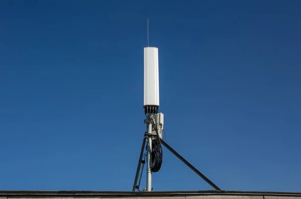 La antena de panel de las bandas GSM DCS UMTS LTE y la unidad de radio son parte del equipo de comunicación de la estación básica se instalan en el techo y el cielo azul como fondo — Foto de Stock