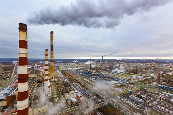 Aerial view of oil and gas industry - refinery in cloudy day - factory - petrochemical plant and a lot of chimneys with smoke and steam.