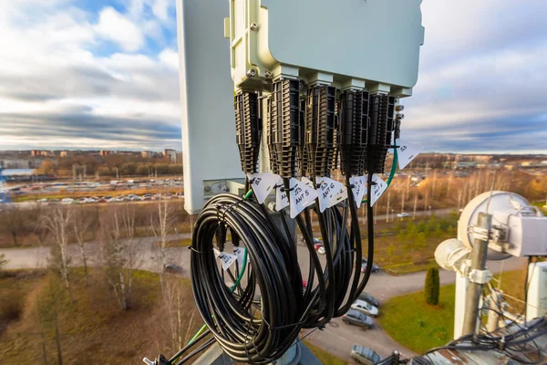 Antena de painel de bandas GSM DCS UMTS LTE, antena GPS e unidade de rádio remoto são como parte do equipamento de comunicação da estação básica são instalados no mastro tubular e céu e cidade são como fundo . — Fotografia de Stock