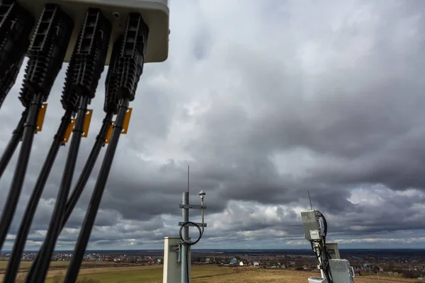 Panel antenna of GSM DCS UMTS LTE bands, GPS antenna and outdoor remote radio unit are as part of communication equipment of basic station are installed on the tubular mast on the roof — Stock Photo, Image