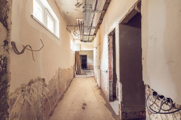 Corredor longo e estreito com janelas, portas, bandejas de cabo e paredes com cabos elétricos não instalados em um apartamento durante a construção, revisão, remodelação, reconstrução, melhorias de casa — Fotografia de Stock