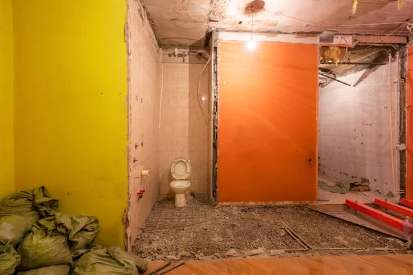 Туалетная комната или туалет со старой унитаз миска, мешки со строительным мусором находятся в квартире, которая находится в стадии строительства, реконструкции, реконструкции, капитального ремонта, расширения, восстановления и реконструкции — стоковое фото