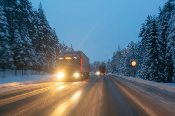 Автомобили ездят с фарами на зимней дороге в снежную бурю в сумерках, когда идет снег. Концепция вождения в опасных условиях с плохой видимостью в зимний период. Изображение с движения — стоковое фото