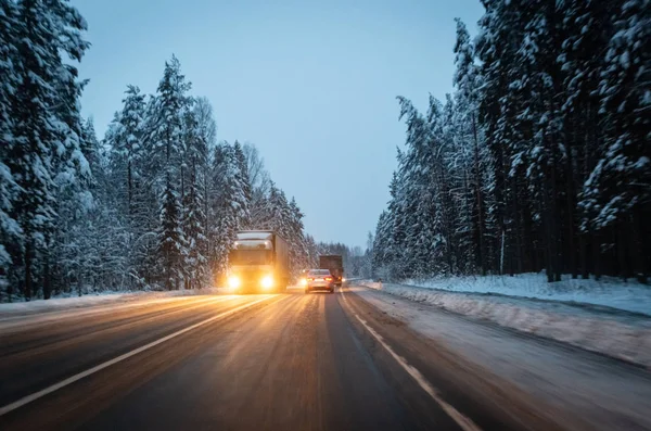 Автомобили ездят с фарами на зимней дороге в снежную бурю в сумерках, когда идет снег. Концепция вождения в опасных условиях с плохой видимостью в зимний период. Изображение с движения — стоковое фото
