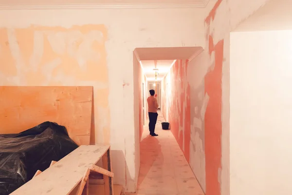 Werknemer is het plafond schilderen door verfroller in gang die een appartement inder bouw is, verbouwing, renovatie, revisie, extensie, herstel en wederopbouw. Concept van home improvement — Stockfoto