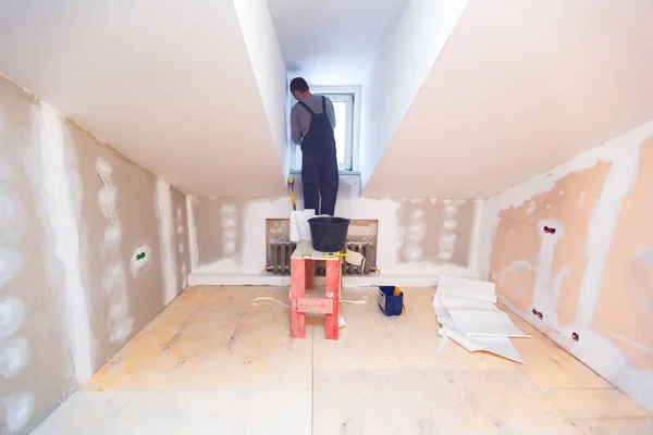 Le travailleur installe une fenêtre en PVC à partir d'une plate-forme en bois dans une petite pièce d'appartement en construction, en rénovation, en rénovation, en révision, en extension, en restauration et en reconstruction. Concept de maison — Photo