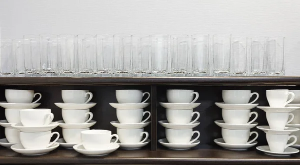 Copos e copos brancos e pires dispostos nas fileiras em buffet no moderno hotel motel ou albergue durante um auto-serviço . — Fotografia de Stock
