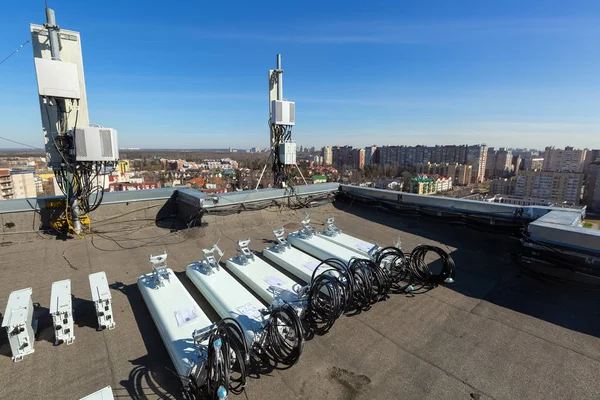 Antenas de painel de bandas GSM DCS UMTS LTE e unidades de rádio ao ar livre são como peças de equipamentos de comunicação da estação básica estão preparados para instalado no telhado e céu e cidade são como fundo — Fotografia de Stock