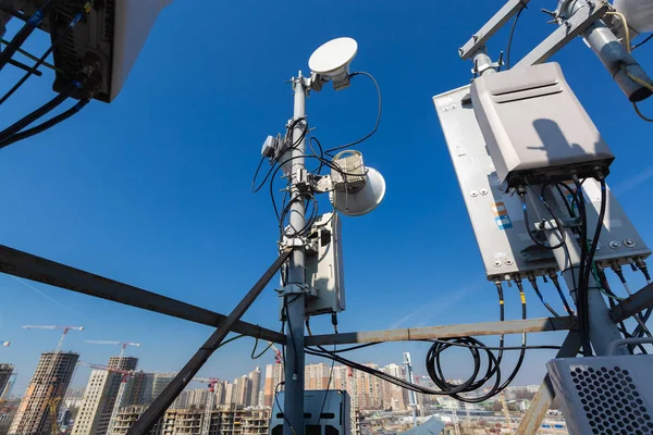 Antena de painel de bandas GSM DCS UMTS LTE e unidade de rádio são como parte do equipamento de comunicação da estação básica são instalados no telhado e céu e cidade são como fundo — Fotografia de Stock