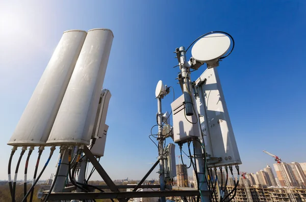 Antenne de panneau des bandes GSM DCS UMTS LTE et unité radio font partie de l'équipement de communication de la station de base sont installés sur le toit et le ciel et la ville sont comme arrière-plan — Photo