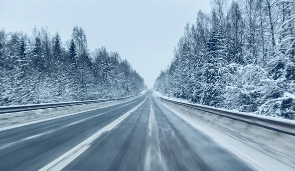 Пустая зимняя дорога в снежную бурю в сумерках, когда летит снег. Концепция вождения в опасных условиях с плохой видимостью в зимний период. Изображение с размытым эффектом движения . — стоковое фото