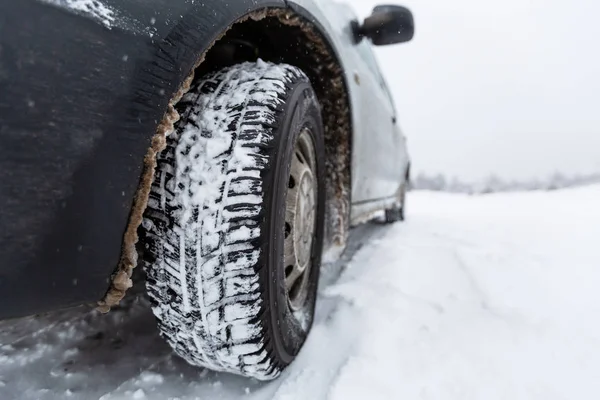 Der Blick richtete sich auf Autoreifen und Stoßstange auf schneebedeckter Straße. Fahrzeug nach Schneefall auf schneeglatter Straße. — Stockfoto