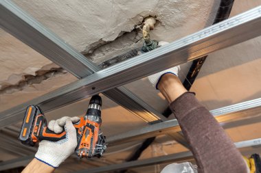 İşçi koruyucu eldivenler ile yapım aşamasında olan daire metal çerçeve yükleme, tadilat, yenileme, revizyon, uzantısı, restorasyon için tavan perforator tarafından sondaj ve