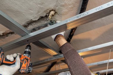 İşçi koruyucu eldivenler ile yapım aşamasında olan daire metal çerçeve yükleme, tadilat, yenileme, revizyon, uzantısı, restorasyon için tavan perforator tarafından sondaj ve