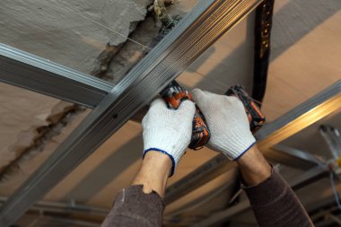 İşçi koruyucu eldivenler ile yapım aşamasında olan daire metal çerçeve yükleme, tadilat, yenileme, revizyon, uzantısı, restorasyon için tavan perforator tarafından sondaj ve