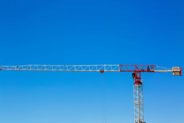 Industrial construction crane or column-jib crane with cabin works  on the construction site and blue sky is a background. Space for your text.