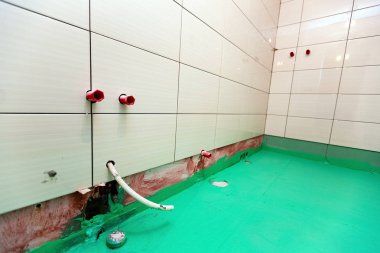 Bathroom with tiled walls and floor painted by green colored waterproof finish material in apartment is inder construction, remodeling, renovation, overhaul, extension, restoration and reconstruction clipart