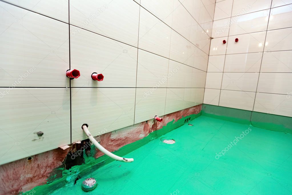 Bathroom with tiled walls and floor painted by green colored waterproof finish material in apartment is inder construction, remodeling, renovation, overhaul, extension, restoration and reconstruction