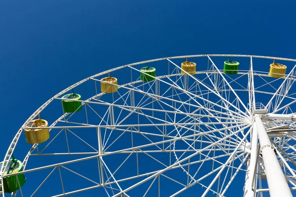 Mavi gökyüzü üzerinde yeşil ve sarı kabinli Beyaz Dönme Dolap