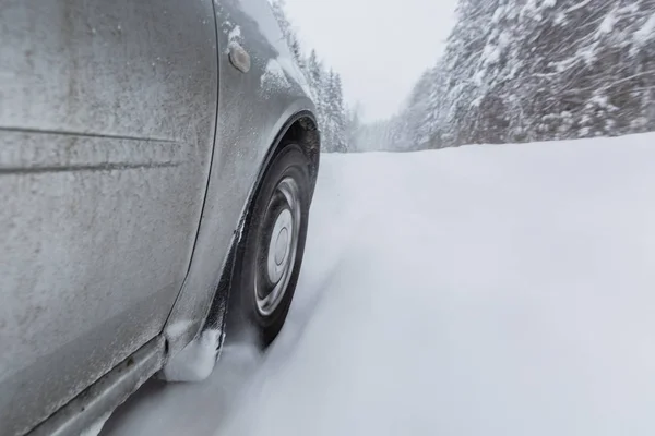 Вид сфокусирован на автомобильной шине во время движения по заснеженной сельской дороге во время снегопада . — стоковое фото