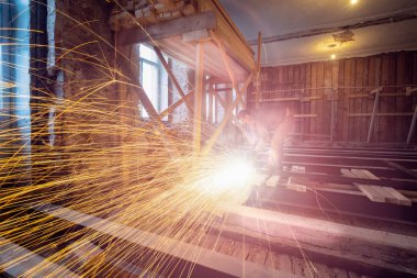 İşçi, inşaat, tadilat, yenileme, uzatma, restorasyon ve yeniden inşa halindeki dairede kıvılcımlar ve fıskiye kullanıyor. Toplam ev iyileştirmesi kavramı.