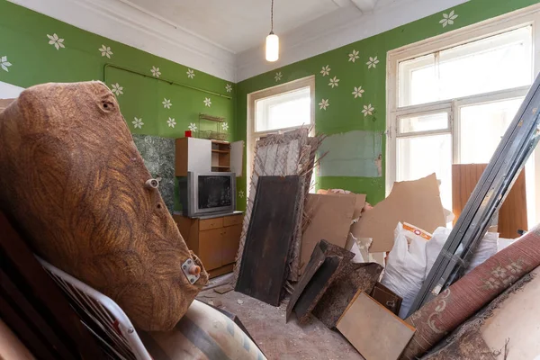 Кухня со сломанной мебелью, телевизором и газовой плитой находится в квартире, которая подготовлена к тотальному строительству, ремонту, пристройке, реставрации и реконструкции . — стоковое фото