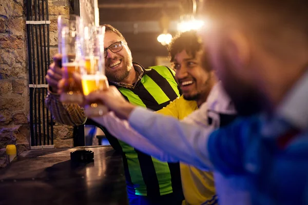 young happy bearded men celebrating and toasting with beer in pub
