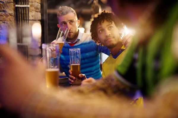 happy male soccer fans drinking beer in pub