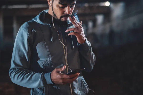 Kulaklık Ile Gece Sokakta Rahatlatıcı Sigara Smartphone Kullanarak Afro Amerikan — Stok fotoğraf