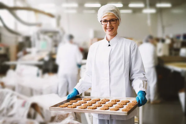 Joven Feliz Trabajadora Sosteniendo Galletas Recién Horneadas Hojalata Fábrica Producción —  Fotos de Stock