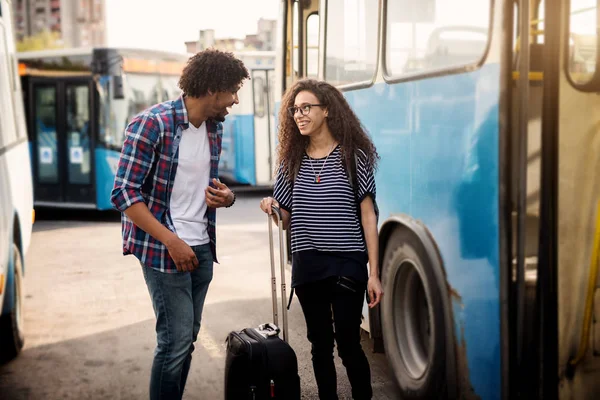 年轻快乐的夫妇站在前面的巴士和他们的手提箱说话 — 图库照片