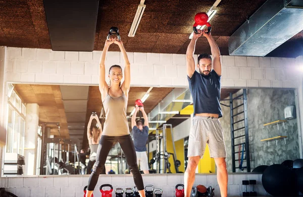 Fuerte Joven Feliz Pareja Levantando Campanas Hervidor Agua Gimnasio Pie —  Fotos de Stock