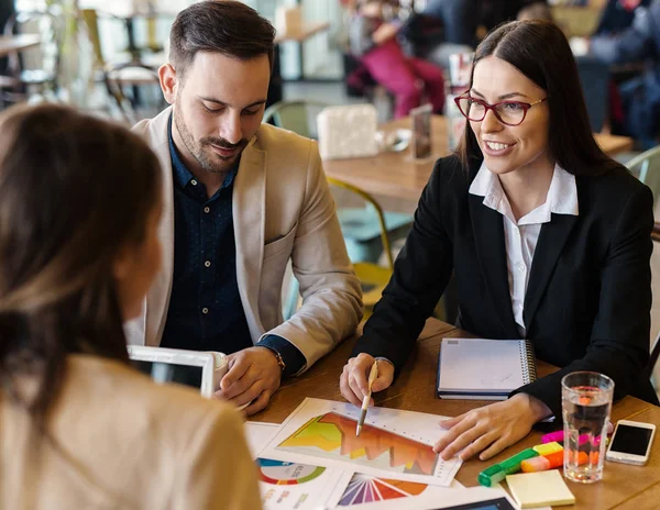 Motivated workers in coffee shop on meeting.Three young colleagues analyzing business