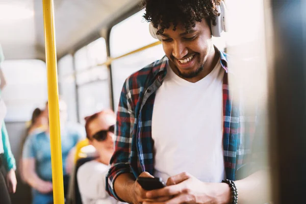 若いハンサムな陽気な男バスに立って 携帯電話を使用して — ストック写真