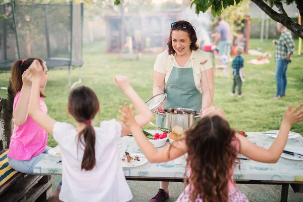 嬉戏的小女孩坐在野餐桌和母亲带来的锅填充新鲜烤肉 — 图库照片