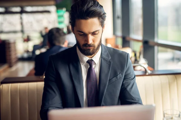 成功的英俊年轻的大胡子生意人在咖啡馆工作与笔记本电脑 — 图库照片
